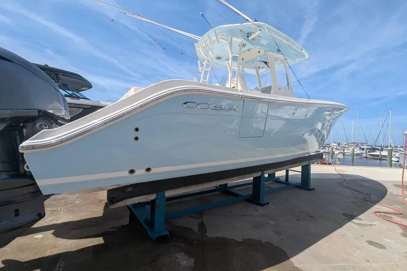 Slide: The Image of 2023 Cobia 301 Center Console boat on a dock, with marina background. - 26