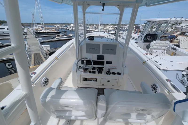 Slide: The Image of 2023 Cobia 301 Center Console boat at marina, featuring dual Garmin displays. - 35