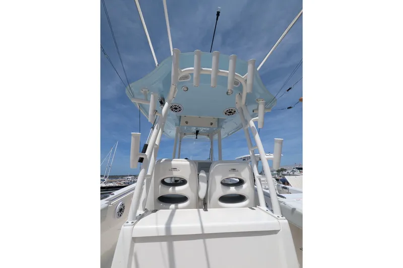 Slide: The Image of 2023 Cobia 301 Center Console boat with rod holders and speakers under a clear blue sky. - 36