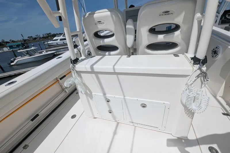 Slide: The Image of 2023 Cobia 301 Center Console boat interior with seating and storage, docked at marina. - 38
