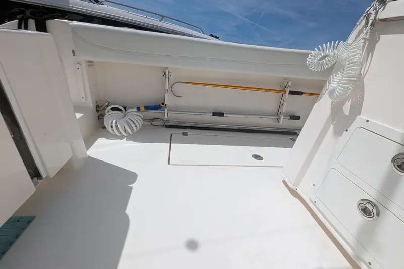 Slide: The Image of 2023 Cobia 301 Center Console boat interior with storage compartments and coiled hose. - 42