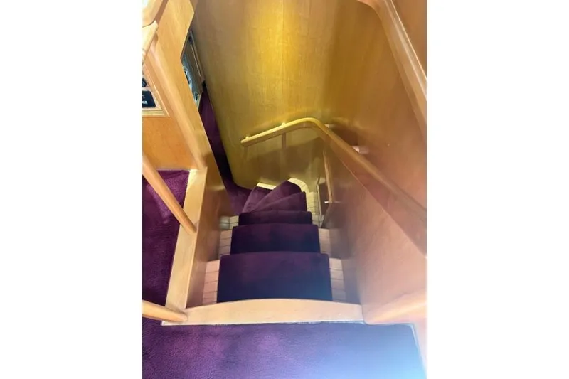 Slide: The Image of Interior staircase of 1999 McKinna 57 Pilothouse yacht with purple carpet and wooden railings. - 18
