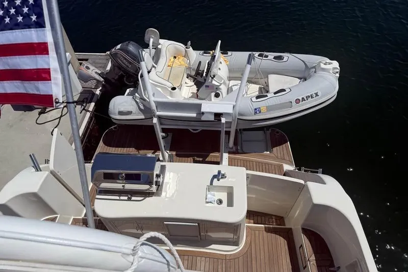 Slide: The Image of 1999 McKinna 57 Pilothouse yacht with dinghy and American flag at dock. - 4