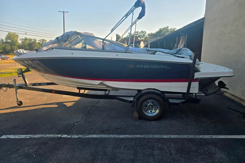 The Image of 2008 Regal 1900 Bowrider boat on trailer, parked outdoors in sunlight. - 1