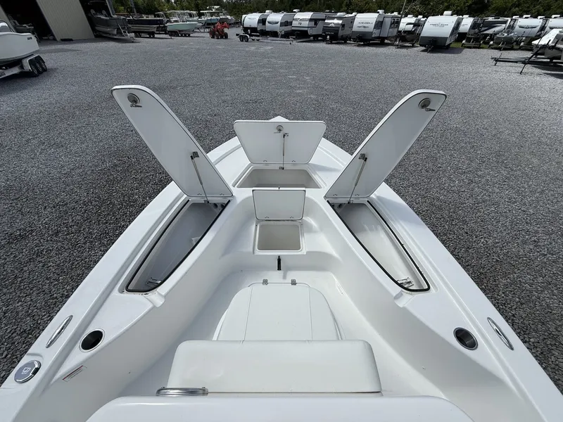 Slide: The Image of 2026 Sea Pro 230 Bay boat with open storage compartments on gravel lot. - 3