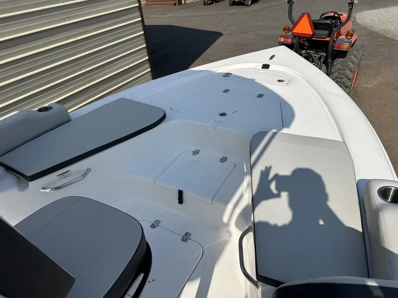 Slide: The Image of 2026 Sea Pro 230 Bay boat with gray seating and tractor in background. - 3