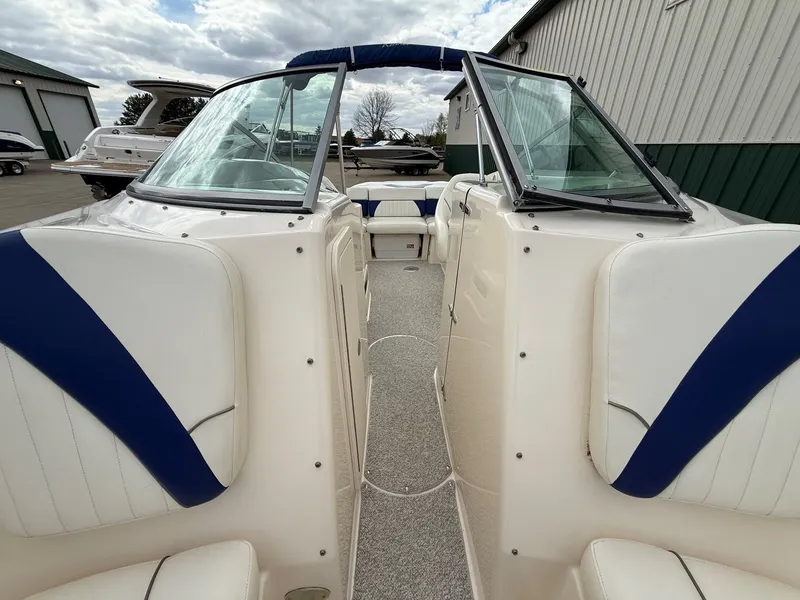 Slide: The Image of 2004 Rinker 262 Captiva Bowrider with blue and white seating outdoors. - 13