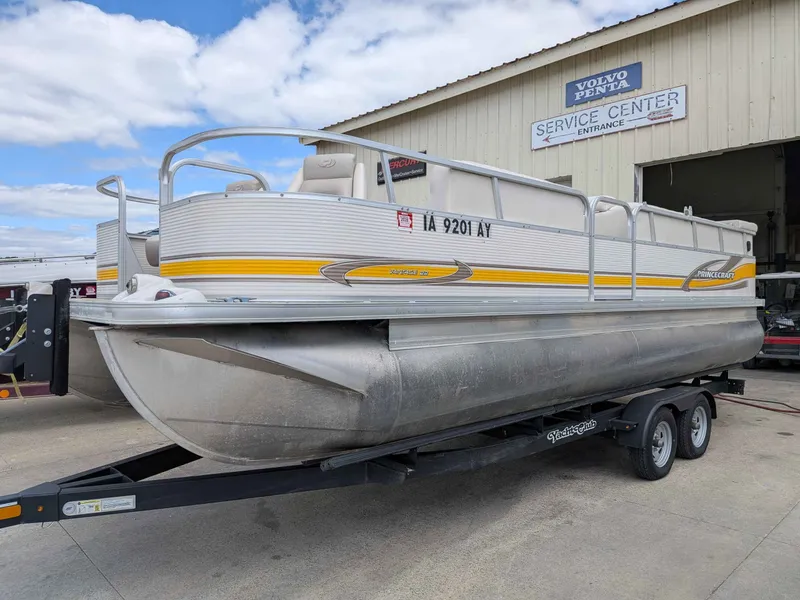 The Image of 2005 Princecraft Pontoon boat on trailer outside service center. - 1