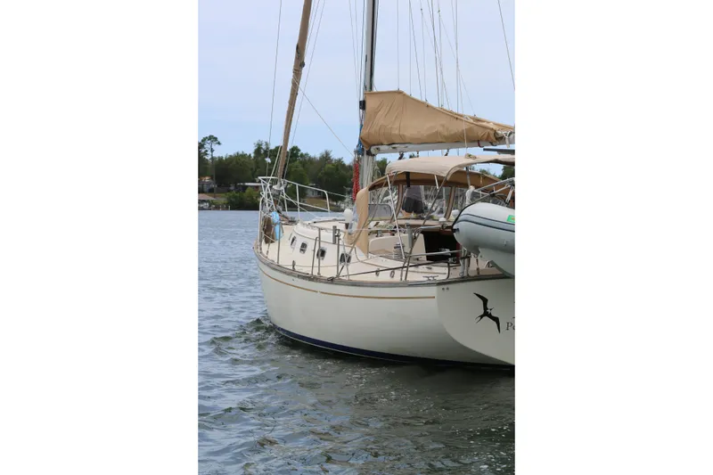 Slide: The Image of 1994 Island Packet 35 sailboat docked on calm water, featuring beige sails and canopy. - 11