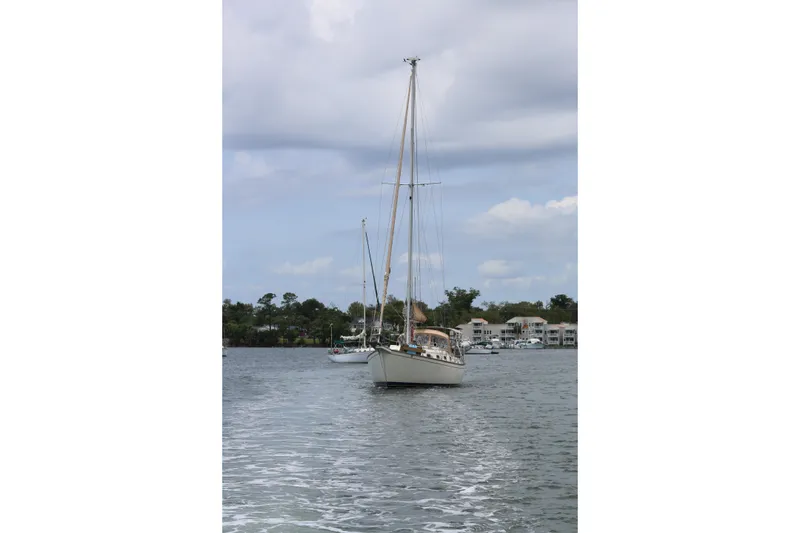 Slide: The Image of Sailboat on water, 1994 Island Packet 35, with cloudy sky and shoreline in background. - 16