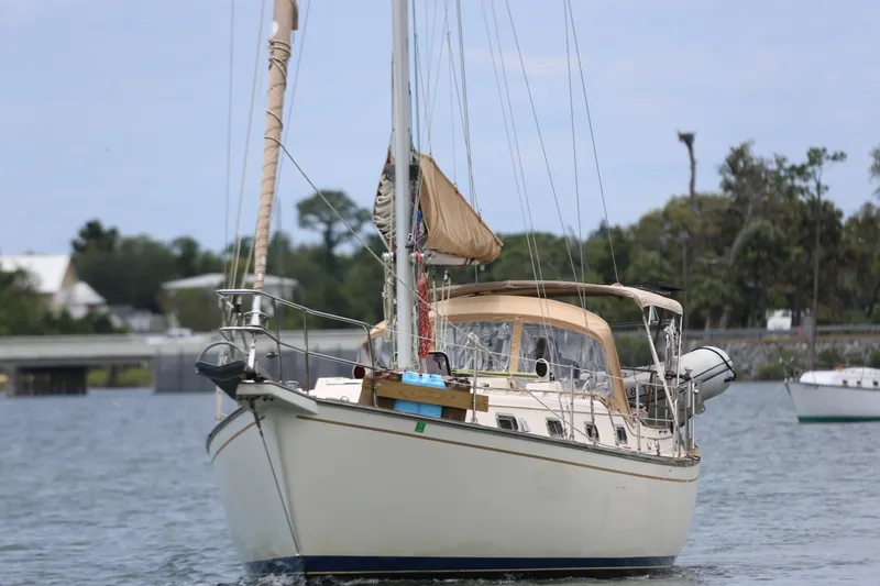 Slide: The Image of 1994 Island Packet 35 sailboat on calm water, featuring tan sails and a spacious deck. - 17