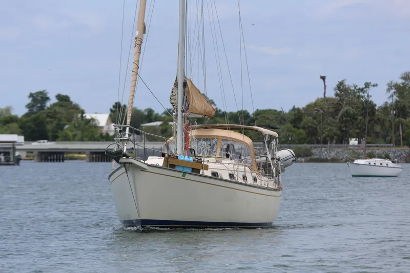 Slide: The Image of 1994 Island Packet 35 sailboat anchored on calm water with trees in the background. - 18