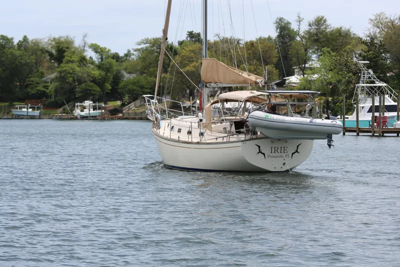 Slide: The Image of 1994 Island Packet 35 sailboat on water, docked near lush shoreline. - 19