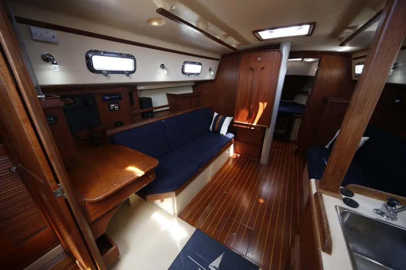 Slide: The Image of Interior of a 1994 Island Packet 35 sailboat, featuring wooden finishes and cozy seating. - 28