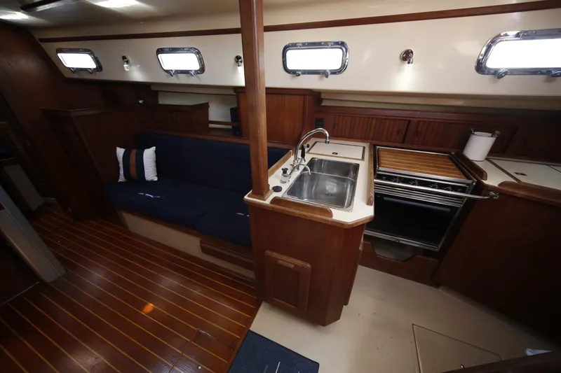 Slide: The Image of Interior of a 1994 Island Packet 35 sailboat, featuring a cozy galley and seating area. - 29