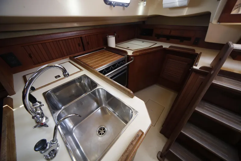 Slide: The Image of 1994 Island Packet 35 yacht kitchen with stainless steel sink and wooden cabinetry. - 30