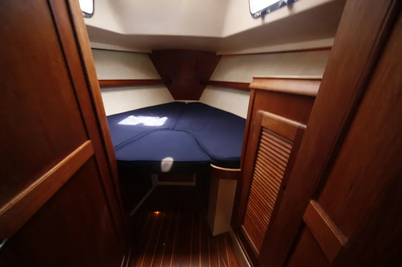 Slide: The Image of 1994 Island Packet 35 sailboat cabin with wooden interior and blue bedding. - 35