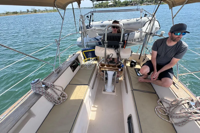 Slide: The Image of Two people relaxing on a 1994 Island Packet 35 sailboat in sunny waters. - 36