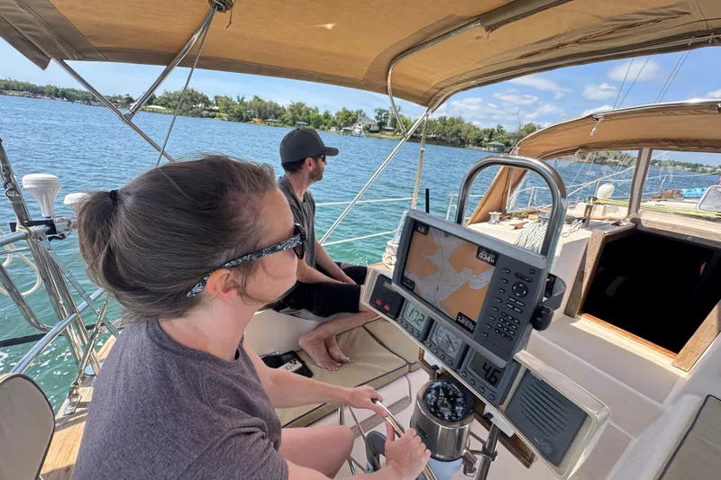Slide: The Image of Two people navigating a 1994 Island Packet 35 sailboat on a sunny day. - 37