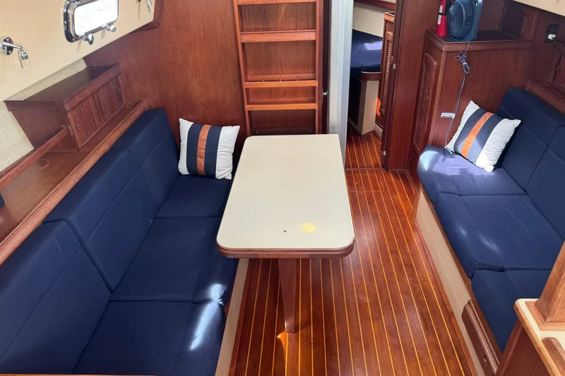 Slide: The Image of Interior of a 1994 Island Packet 35 sailboat with wooden flooring and blue seating. - 43