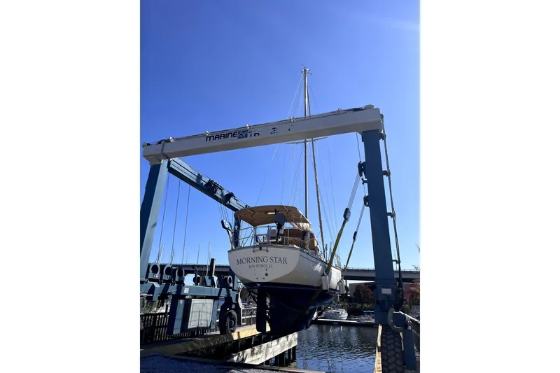 Slide: The Image of 1994 Island Packet 35 sailboat in a marina lift under clear blue sky. - 46