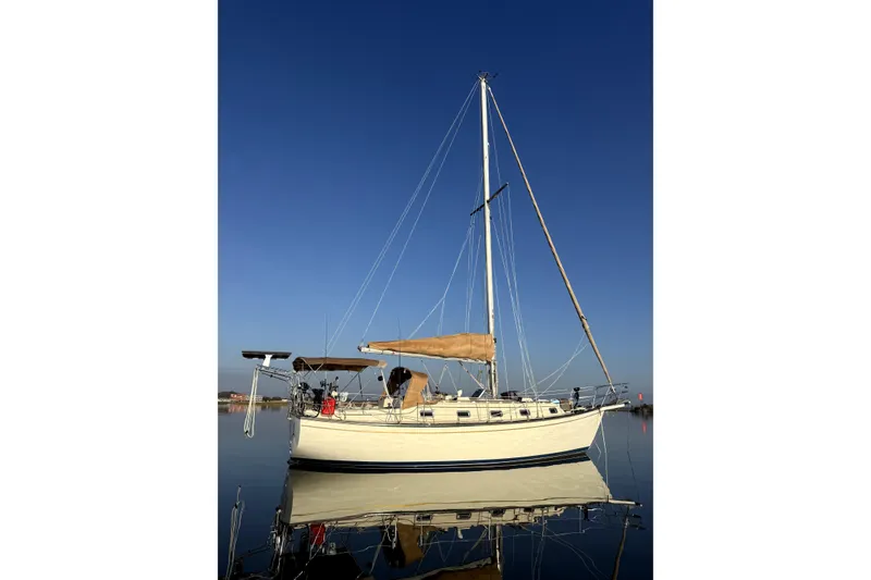 Slide: The Image of 1994 Island Packet 35 sailboat on calm water under clear blue sky. - 47