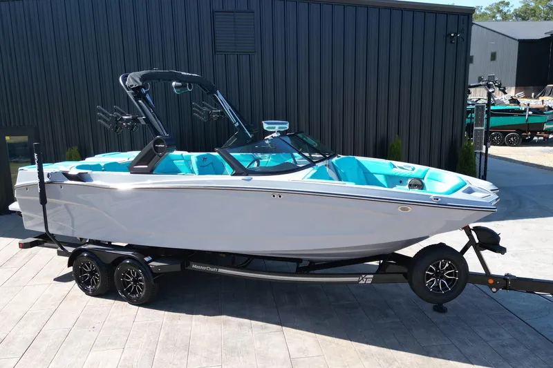 The Image of 2025 MasterCraft XT24 boat on trailer, featuring sleek design and turquoise interior. - 0