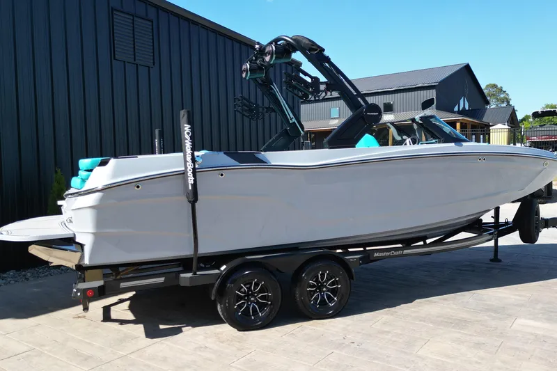 Slide: The Image of 2025 MasterCraft XT24 boat on trailer, sleek design, parked outdoors. - 2