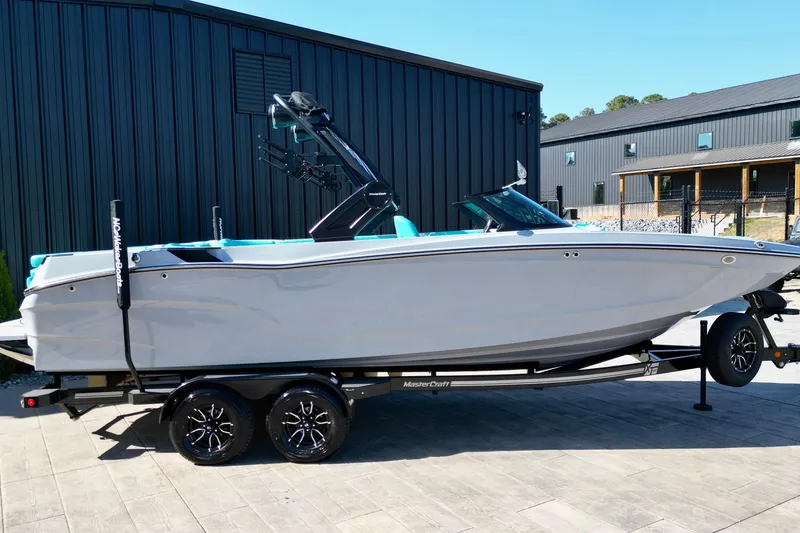 Slide: The Image of 2025 MasterCraft XT24 boat on trailer, parked outside modern building. - 20