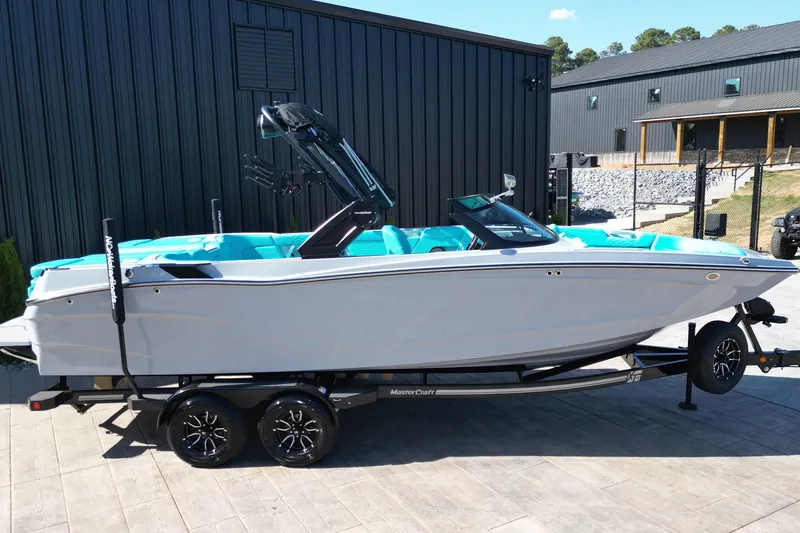 Slide: The Image of 2025 MasterCraft XT24 boat on trailer, parked outdoors near modern buildings. - 3