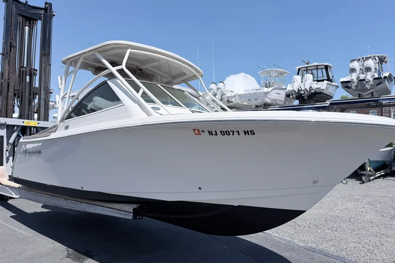 Slide: The Image of 2021 Sailfish 245 DC boat on trailer, displayed outdoors with other boats in background. - 23