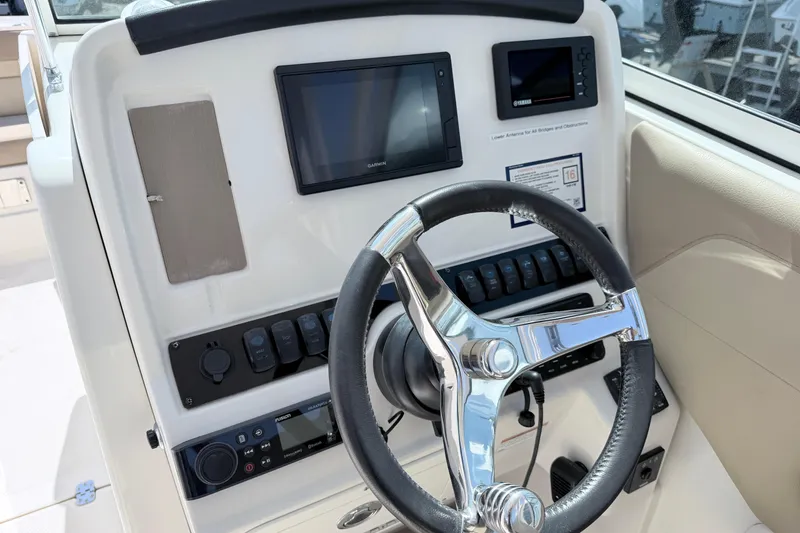 Slide: The Image of 2021 Sailfish 245 DC boat dashboard with steering wheel and electronic controls. - 33