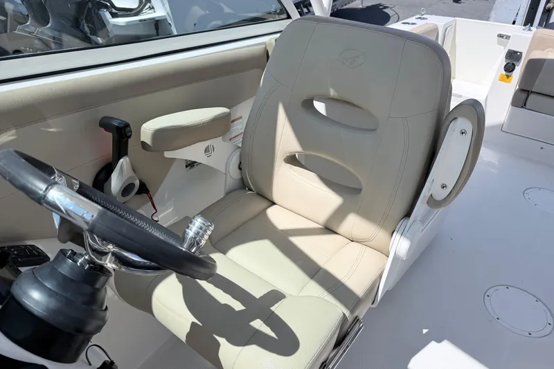 Slide: The Image of 2021 Sailfish 245 DC boat interior with beige captain's chair and steering wheel. - 34