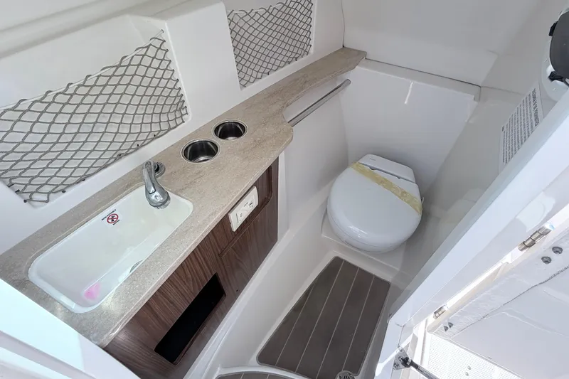 Slide: The Image of 2021 Sailfish 245 DC boat interior with sink, toilet, and storage netting. - 37