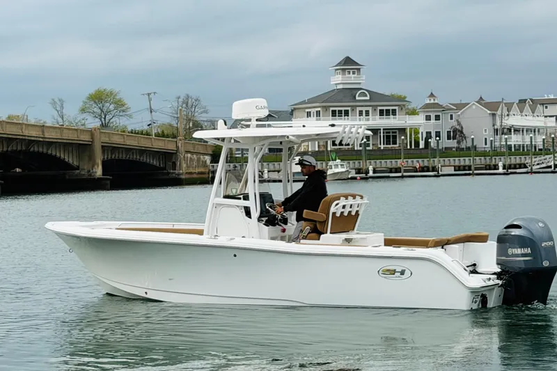 Slide: The Image of 2022 Sea Hunt Ultra 234 boat cruising near a bridge and waterfront buildings. - 3
