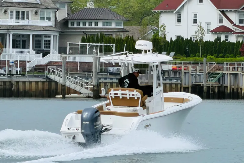 Slide: The Image of 2022 Sea Hunt Ultra 234 boat cruising near waterfront homes. - 4