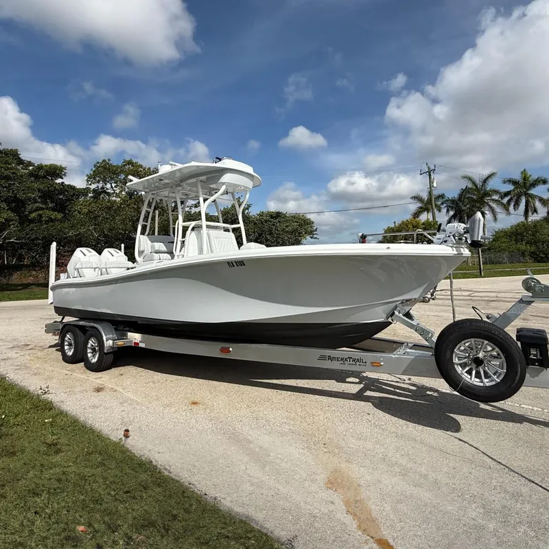 The Image of 2026 Yellowfin 26 Hybrid boat on trailer, parked outdoors under a blue sky. - 0