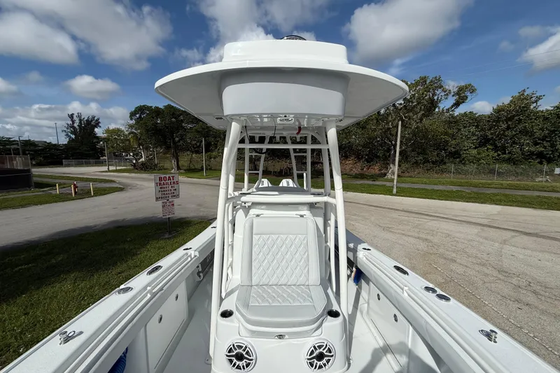 Slide: The Image of 2026 Yellowfin 26 Hybrid boat with T-top and seating, parked near a road. - 10