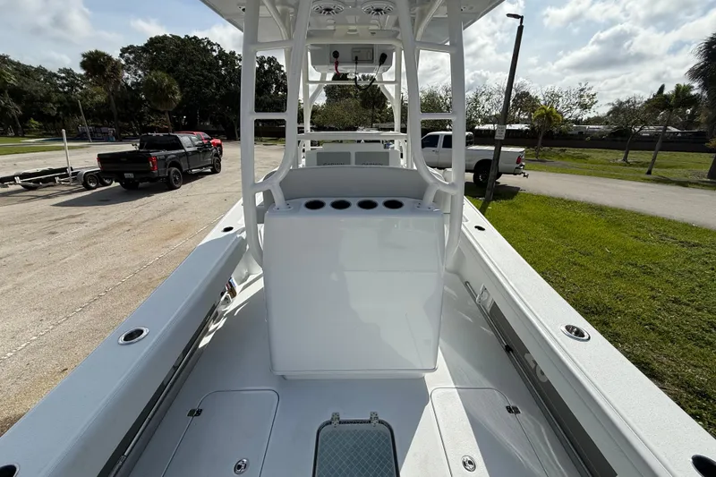 Slide: The Image of 2026 Yellowfin 26 Hybrid boat interior with console and rod holders, parked near trucks. - 18