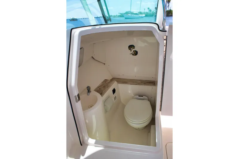 Slide: The Image of 2018 Pursuit DC 265 Dual Console boat interior with compact marine toilet and sink. - 14