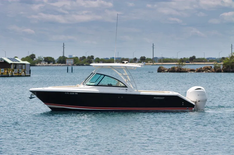 Slide: The Image of 2018 Pursuit DC 265 Dual Console boat on calm water, side view. - 16