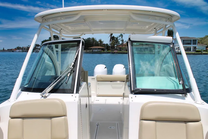 Slide: The Image of 2018 Pursuit DC 265 Dual Console boat on water, showcasing seating and windshield. - 19