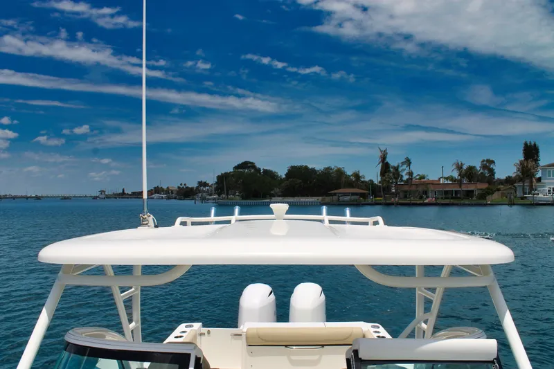 Slide: The Image of 2018 Pursuit DC 265 Dual Console boat on calm water under a clear blue sky. - 21