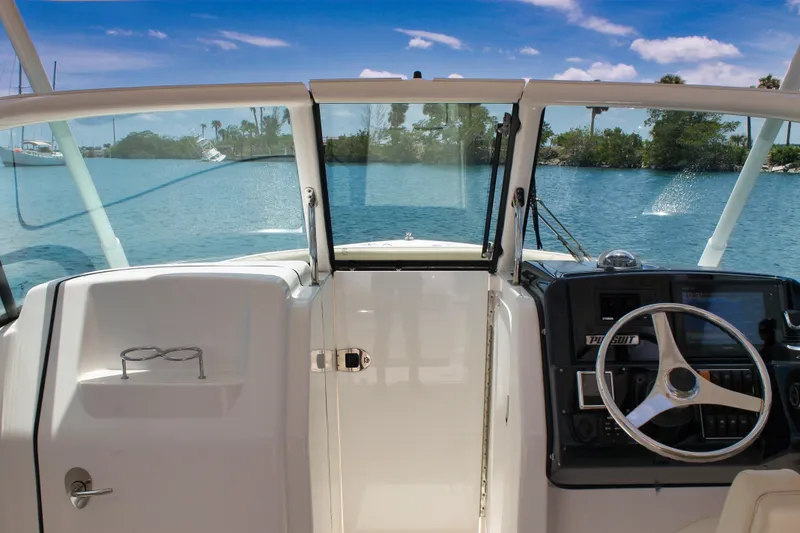 Slide: The Image of 2018 Pursuit DC 265 Dual Console boat interior with steering wheel and open water view. - 24