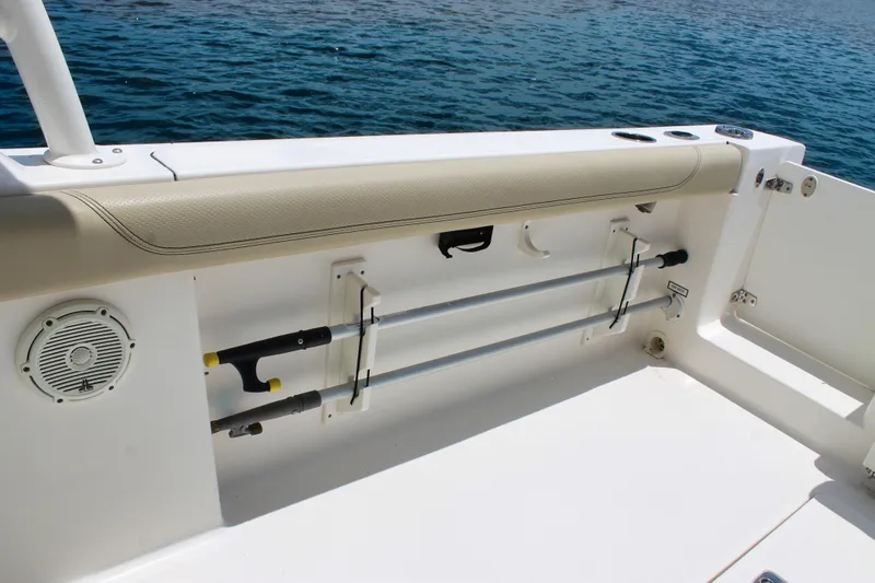 Slide: The Image of 2018 Pursuit DC 265 Dual Console boat interior with rod holders and speaker by the water. - 26