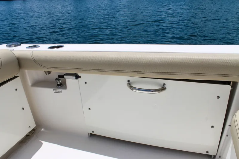 Slide: The Image of 2018 Pursuit DC 265 Dual Console boat interior with storage compartment and ocean view. - 27