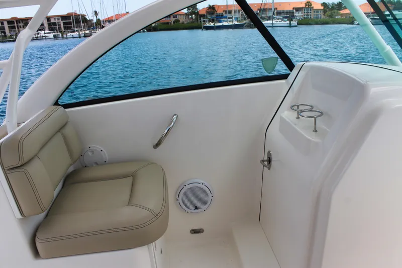 Slide: The Image of 2018 Pursuit DC 265 Dual Console interior with beige seating and cup holders. - 33