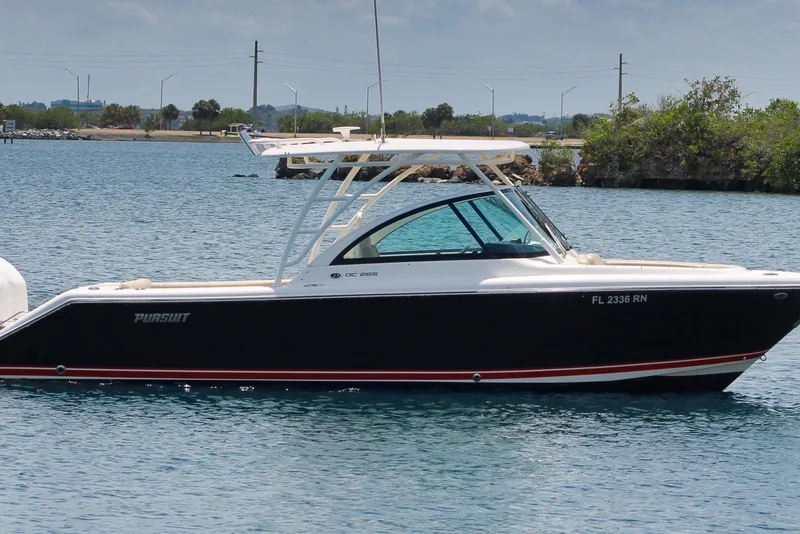Slide: The Image of 2018 Pursuit DC 265 Dual Console boat on calm water, side view. - 4