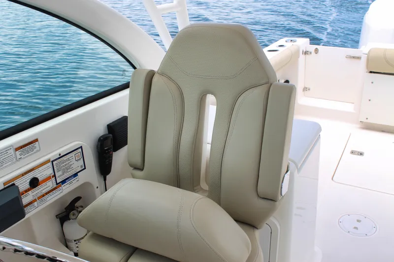 Slide: The Image of Captain's seat on 2018 Pursuit DC 265 Dual Console boat, overlooking calm blue water. - 42