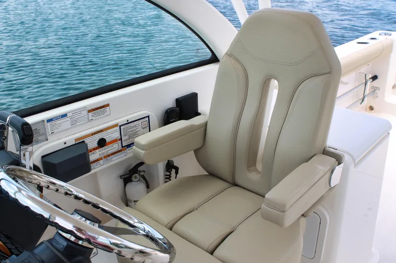 Slide: The Image of Captain's seat on 2018 Pursuit DC 265 Dual Console boat, overlooking water. - 43